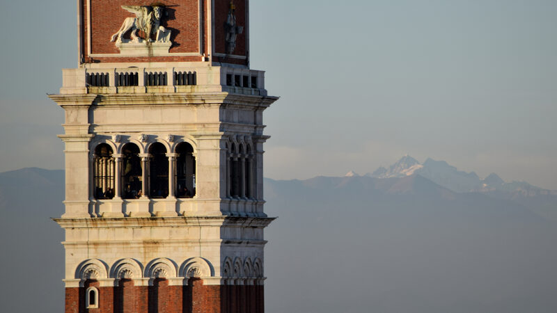 From Above : Close up view of the Campanile di San Marco with the snowy Alps in the background