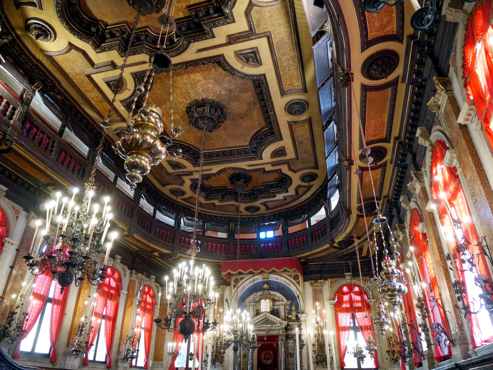 Ghetto Ebraico : The ornate interior features large chandeliers and a massive sculpted wooden ceiling.