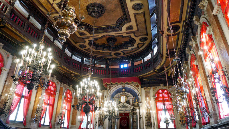 Ghetto Ebraico : The ornate interior features large chandeliers and a massive sculpted wooden ceiling.