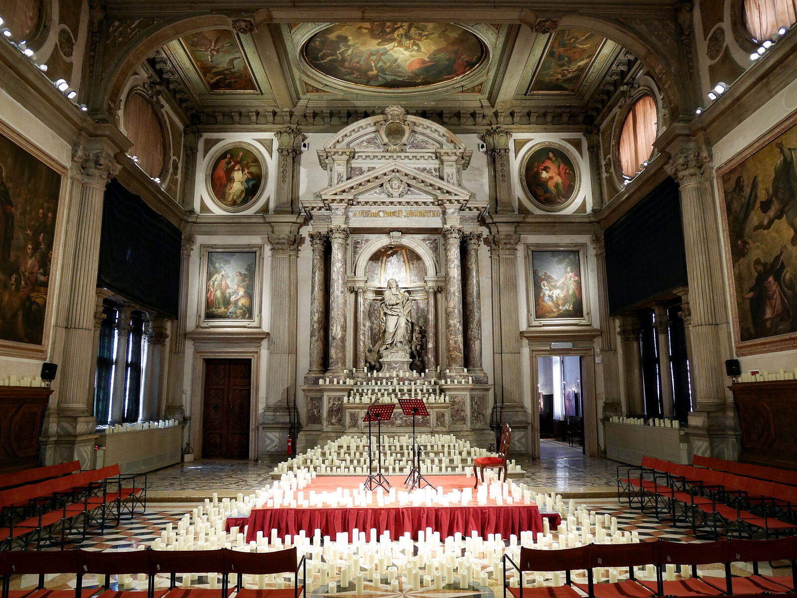 Scuola Grande San Giovanni : A menudo hay velas dispuestas ante la estatua de San Juan, ya que el espacio se usa con frecuencia para conciertos a la luz de las velas