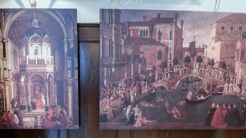 Scuola Grande San Giovanni : En la Cancillería se ven reproducciones fotográficas a escala reducida del célebre ciclo de grandes lienzos sobre los Milagros de la Vera Cruz, encargado por la Scuola a finales del siglo XV. Ubicación actual de los originales: Galería de la Academia.